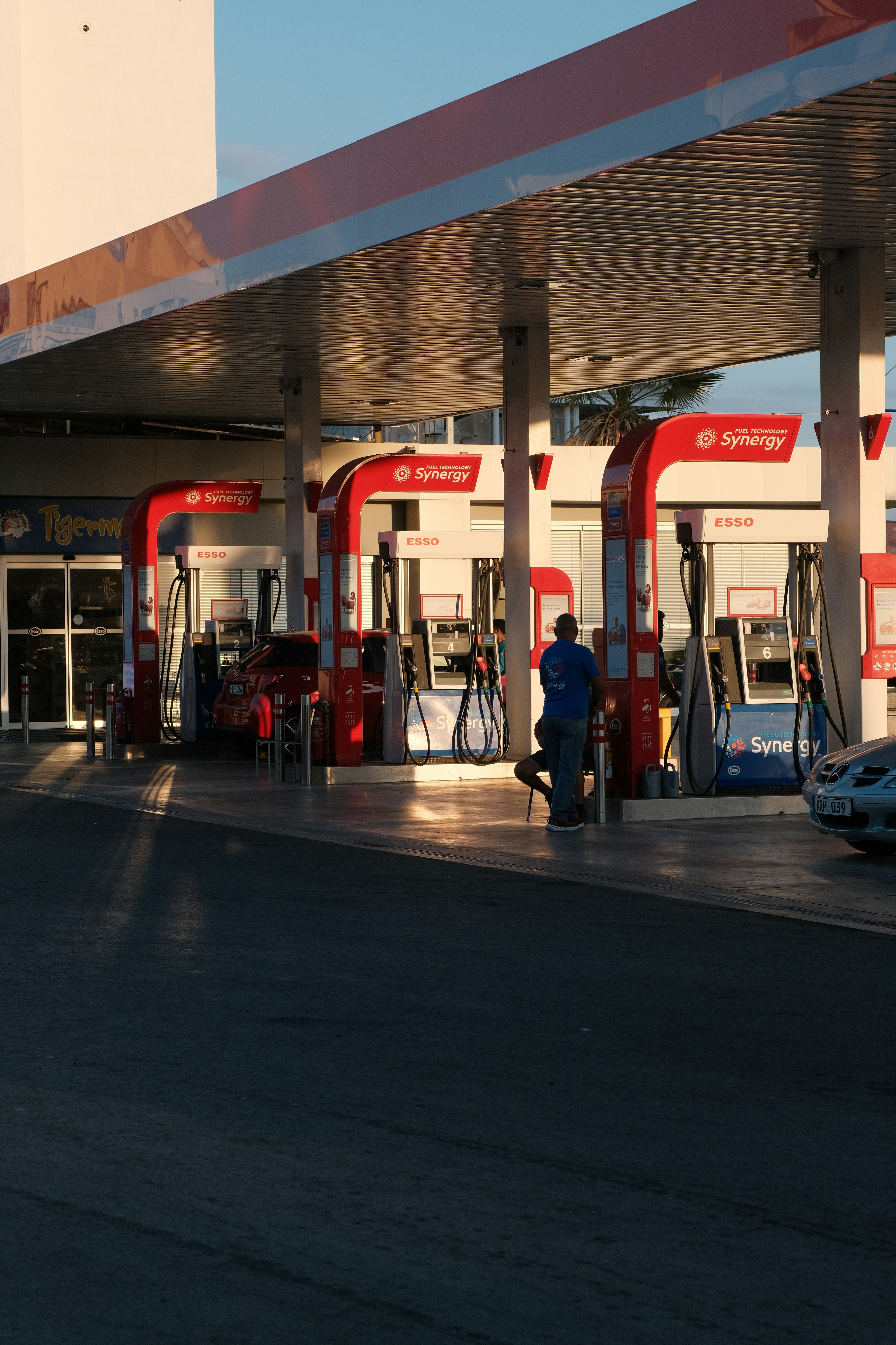 Man at gas station pumps at sunset